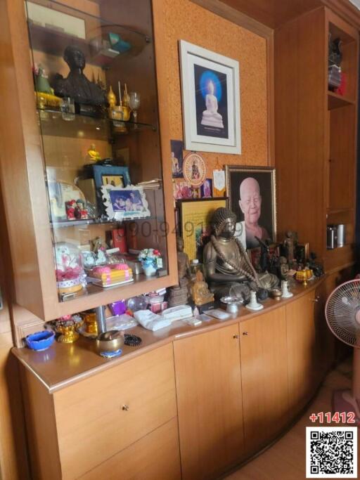 Living room with display cabinet showcasing personal memorabilia and religious statues