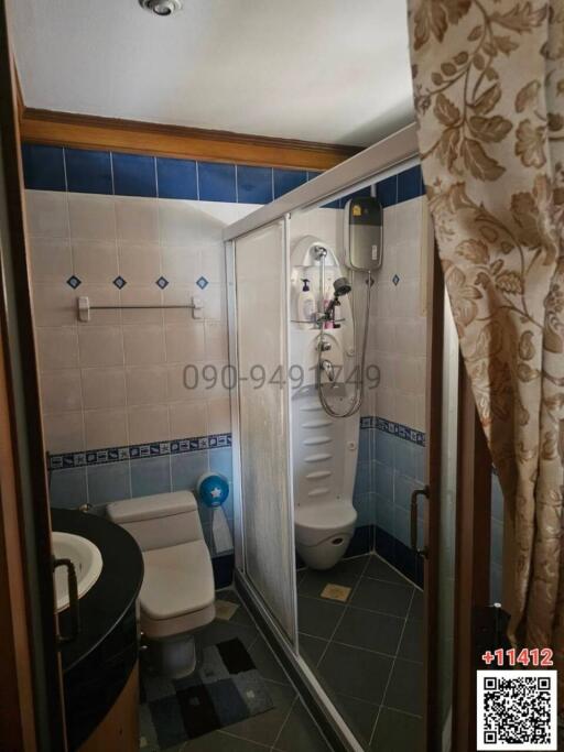 Compact bathroom with shower cabin, toilet and patterned tiles