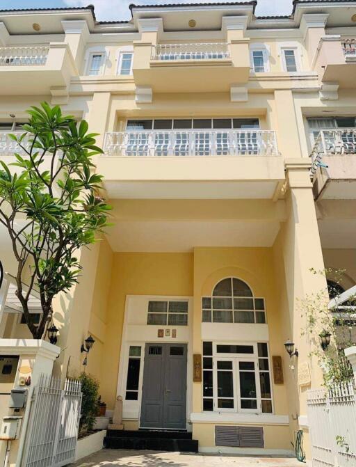 Elegant yellow townhouse with a balcony and large windows