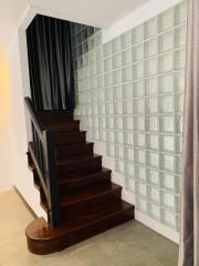 Elegant staircase with wooden steps and glass block wall