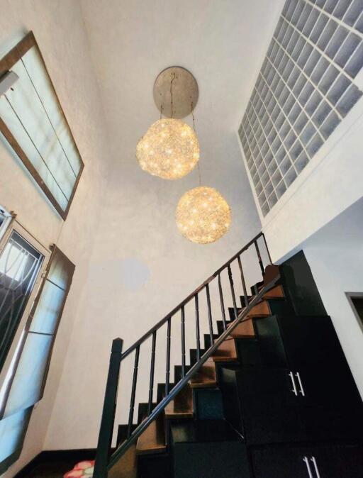 Modern staircase with decorative hanging lights and high ceiling