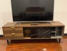 Modern living room with a large flat-screen TV and wooden media console on polished hardwood floor