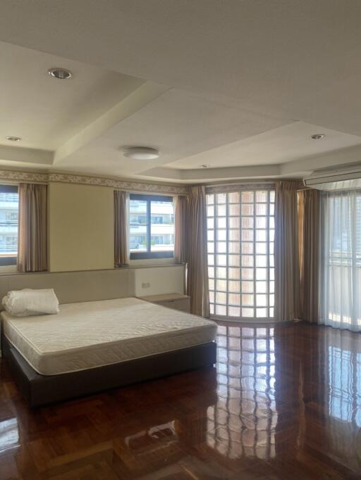 Spacious bedroom with parquet flooring and large windows