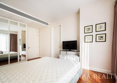 Spacious and well-lit bedroom with mirrored closet and flat-screen TV