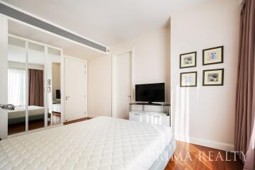 Spacious and well-lit bedroom with mirrored closet and flat-screen TV