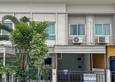 Exterior view of a modern residential townhouse with front garden and gated entrance