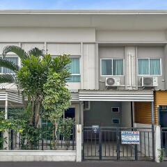 Exterior view of a modern residential townhouse with front garden and gated entrance