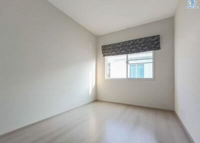 Bright empty bedroom with a large window and hardwood floors