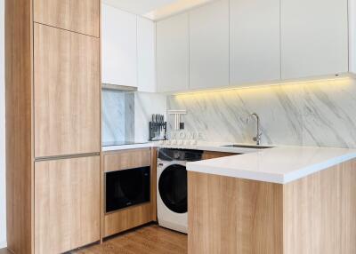 Modern kitchen with white cabinetry, marble backsplash, and built-in appliances