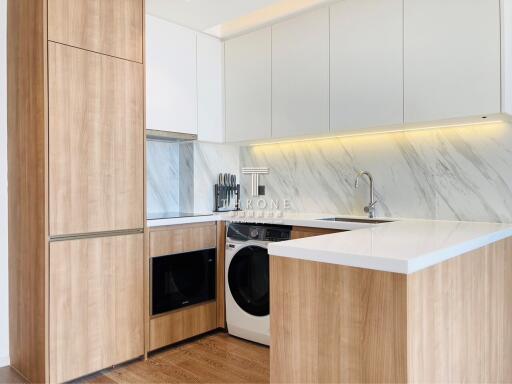 Modern kitchen with white cabinetry, marble backsplash, and built-in appliances