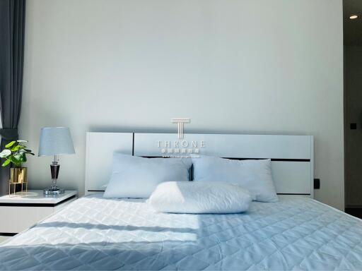 Modern bedroom with a comfortable king-sized bed, elegant bedding, side lamp, and a decorative plant