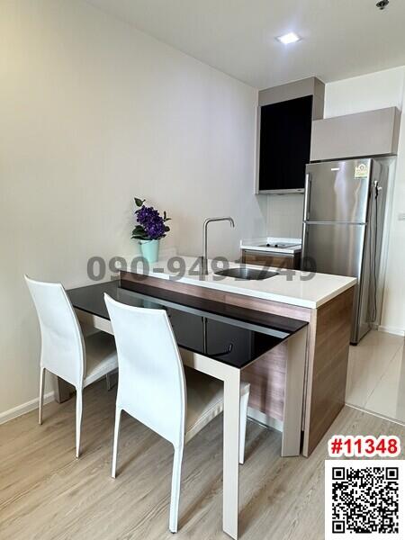 Modern compact kitchen with dining area and stainless steel refrigerator