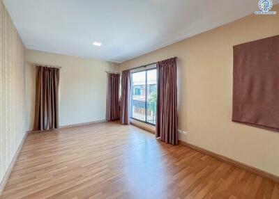 Spacious empty living room with hardwood flooring and large windows with curtains