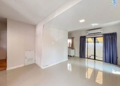 Spacious and well-lit living room with glossy tiled flooring and sliding doors leading to a balcony