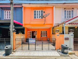 Bright orange two-story residential building with balcony and gated entrance