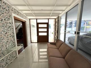 Spacious entrance hall with terrazzo flooring and modern sofa, leading to a well-lit living space