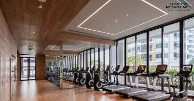 Modern gym facility in residential building with large windows and wooden accents