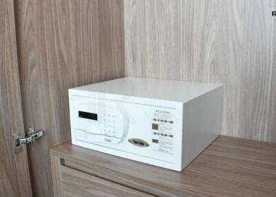 Safety amenities in modern apartment bedroom showcasing a digital safe on a wooden cabinet