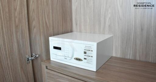 Safety amenities in modern apartment bedroom showcasing a digital safe on a wooden cabinet