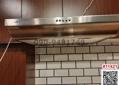 Stainless steel range hood over modern subway tile backsplash in a kitchen