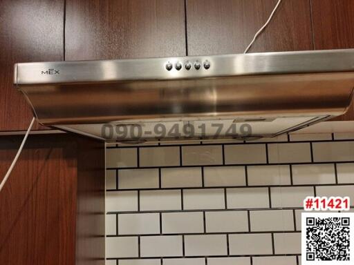 Stainless steel range hood over modern subway tile backsplash in a kitchen