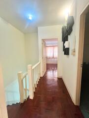 Brightly lit hallway with wooden floors and white walls