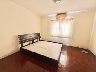 Spacious bedroom with wooden flooring and large window