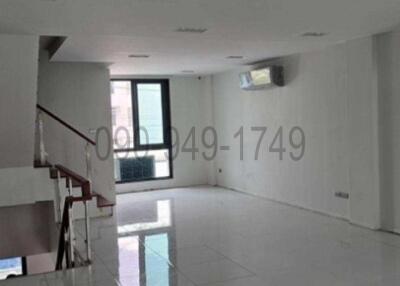 Spacious and well-lit empty living room with staircase and balcony access