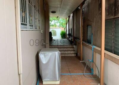 Covered walkway outside of a house with tile flooring and garden access
