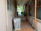 Covered walkway outside of a house with tile flooring and garden access