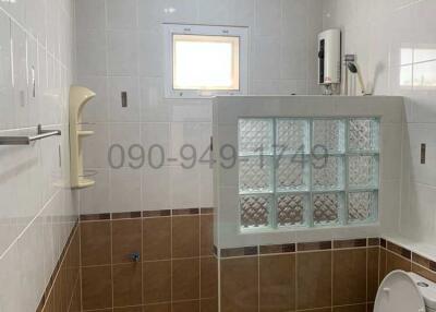 Modern bathroom interior with white and brown tiles, glass partition, and essential appliances