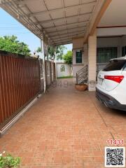 Paved driveway with covered parking space and partial view of a vehicle