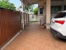 Paved driveway with covered parking space and partial view of a vehicle