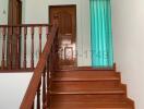 Wooden staircase with handrails leading to the upper level of a house