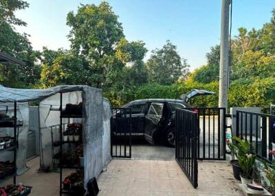 Paved patio area with vehicle parking and potted plants under a shelter