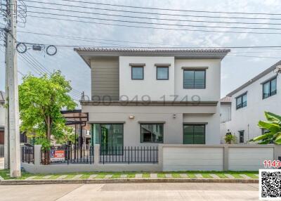 Modern two-story residential home with a gray façade and a front yard behind a white fence