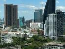 Cityscape view from a high-rise apartment window with various buildings under a clear blue sky