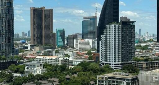 Cityscape view from a high-rise apartment window with various buildings under a clear blue sky