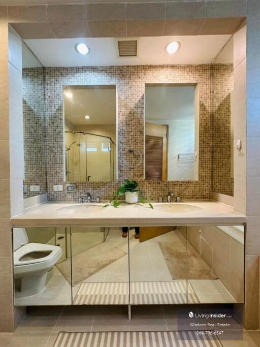 Modern bathroom interior with mosaic tile walls, large mirror, and white fixtures