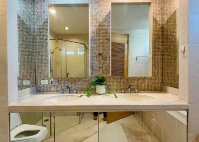 Modern bathroom interior with mosaic tile walls, large mirror, and white fixtures