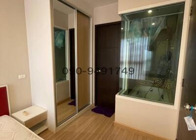 Cozy bedroom with wooden flooring and an adjacent bathroom seen through a glass wall