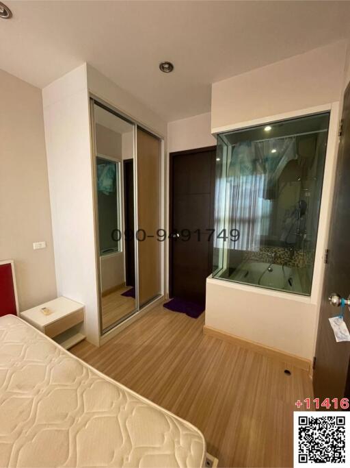 Cozy bedroom with wooden flooring and an adjacent bathroom seen through a glass wall