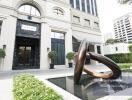 Luxury building entrance with artistic sculpture and water feature