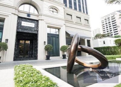 Luxury building entrance with artistic sculpture and water feature
