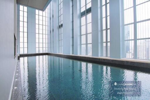 Indoor swimming pool with large windows and city view