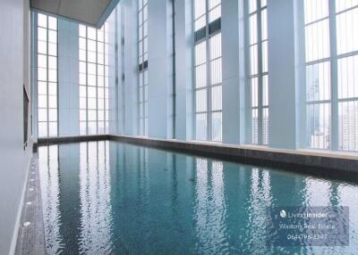 Indoor swimming pool with large windows and city view