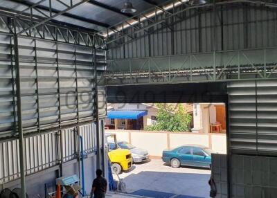 Spacious warehouse interior with open gate and visible cars