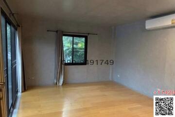 Spacious unfurnished bedroom with hardwood floors and a view of greenery outside the window