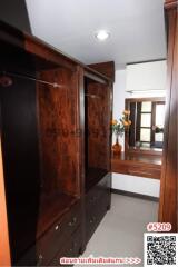 Spacious wardrobe in an interior room with a glimpse of the adjacent room featuring a mirror and shelf