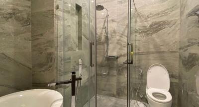 Modern bathroom with glass shower enclosure and marble walls